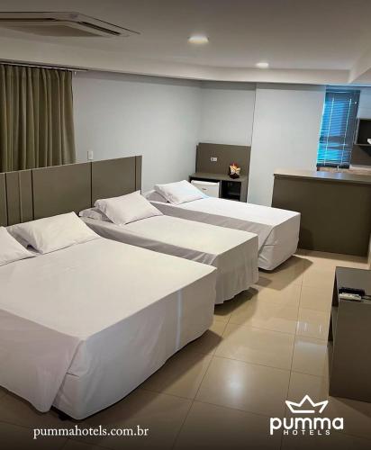 a hotel room with three beds and a kitchen at Pumma Business Hotel in Canaã dos Carajás