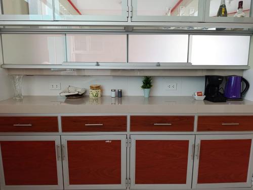 a kitchen with white and red cabinets and a counter at Casa de campo valle de Pachia - Fundo Paris in Huaycuyo