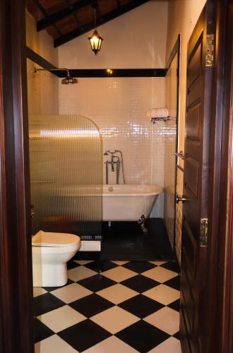 a bathroom with a tub and a toilet and a sink at The Hallery By Old Kent in Madikeri