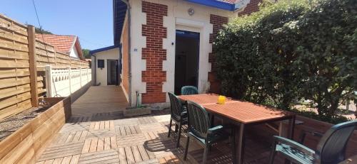 une table et des chaises en bois sur une terrasse dans l'établissement Soulac, à 150m de la plage et proche centre-ville maison 8 personnes, à Soulac-sur-Mer