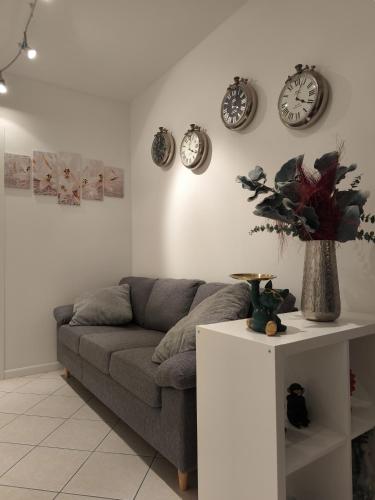 a living room with a couch and clocks on the wall at Atmosphere Guest House Rubiera in Rubiera