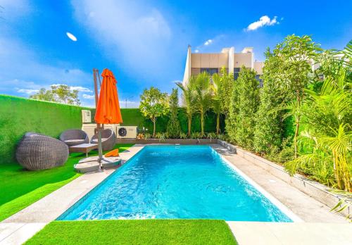 a swimming pool in a backyard with an orange umbrella at Dubai Private Pool villa Damac Hills 2 deleguest in Dubai