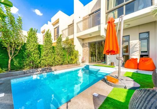 a swimming pool with an orange umbrella next to a building at Dubai Private Pool villa Damac Hills 2 deleguest in Dubai