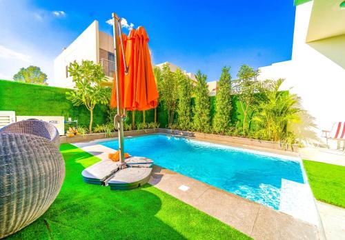 a swimming pool with an orange umbrella in a yard at Dubai Private Pool villa Damac Hills 2 deleguest in Dubai