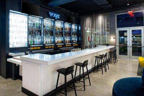 a bar in a restaurant with stools at Aloft North Kansas City in Kansas City