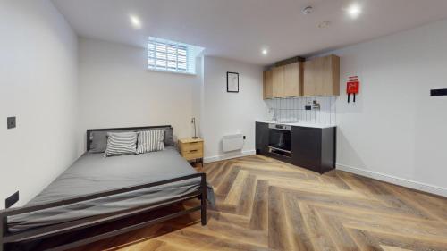 a bedroom with a large bed and a kitchen at The Thurloe Studios in Manchester