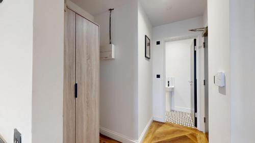 a hallway with white walls and a wooden door at The Thurloe Studios in Manchester