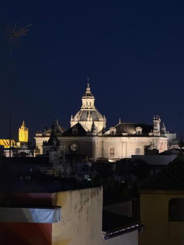 a large white building at night with a city at Aquitania Home Suites in Seville