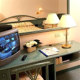 um quarto com uma cama e uma secretária com uma televisão em Hotel Italia em Bellaria-Igea Marina