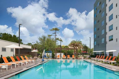 a swimming pool with lounge chairs and a building at Aloft Orlando at SeaWorld in Orlando