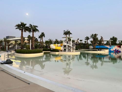 a pool of water in a resort with palm trees at Dubai Private Pool villa Damac Hills 2 deleguest in Dubai