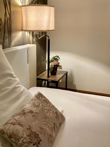 a bed with a pillow and a table with a lamp at La Villa des Roses Gîte Chambres d'hôtes Piscine chauffée in Luçon