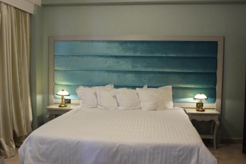 a bedroom with a white bed with a blue headboard at Phoenicia Grand Hotel in Bucharest