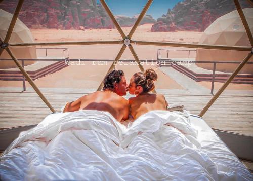 a man and a woman laying in bed at Wadi Rum Relaxation Camp in Wadi Rum