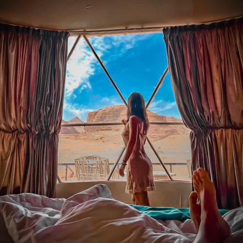 a woman standing in a window looking out at the desert at Wadi Rum Relaxation Camp in Disah