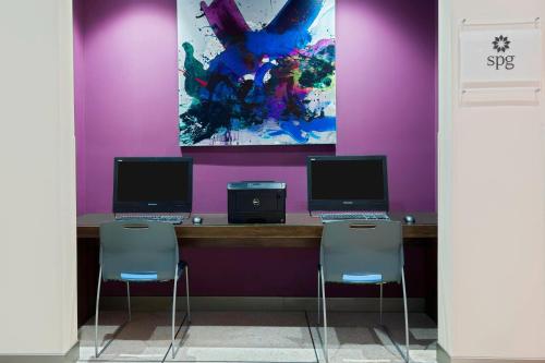 two computers sitting on a desk with two chairs at Aloft Orlando Downtown in Orlando