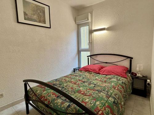 une chambre avec un lit avec des oreillers rouges et une fenêtre dans l'établissement Appartement 2 pièces - 4 personnes - AR070-B19, à Argelès-sur-Mer
