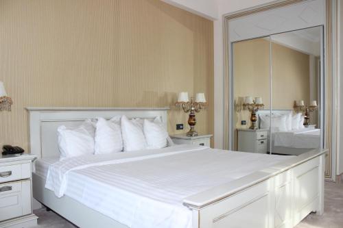 a bedroom with a large white bed with a large mirror at Phoenicia Grand Hotel in Bucharest