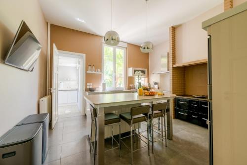 une cuisine avec un grand îlot et des tabourets de bar dans l'établissement L'Artbanne - Maison Gaïa, à Saint-Hilaire-le-Petit