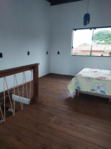 a room with a bed and a table and a window at Casa da Paz -Praia do Rosa in Imbituba