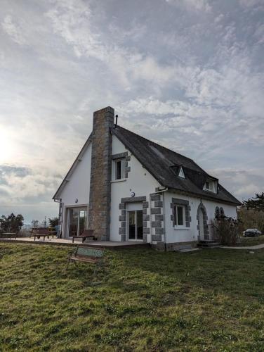 una casa blanca con chimenea en la parte superior de un campo en Maison familiale 6 chambres, vue imprenable, en Pléboulle