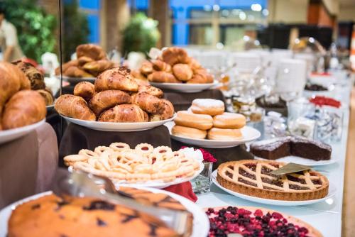 a table topped with plates of pastries and pies at Hotel Veronesi La Torre in Dossobuono