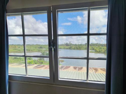 a window with a view of a river seen through it at Appartement Ecovilla Blauwmeer in Paranam