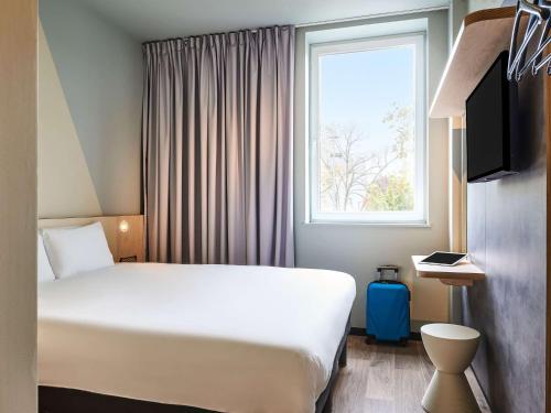 a hotel room with a bed and a window at ibis budget Toulouse Labège in Labège