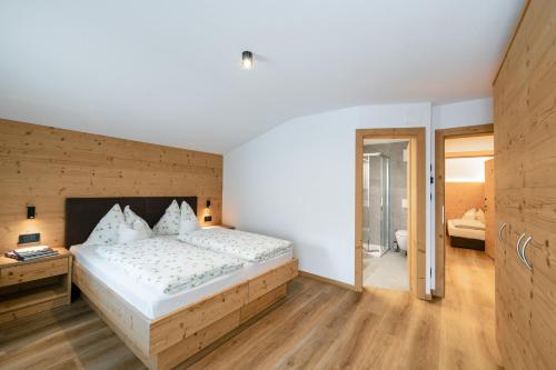 a bedroom with a large bed with a wooden wall at Garni Edera in Corvara in Badia