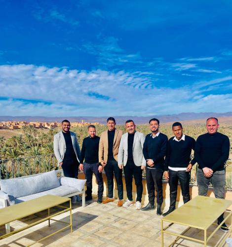 a group of men posing for a picture on a patio at Hotel Kasbah Ennakhile in Nkob
