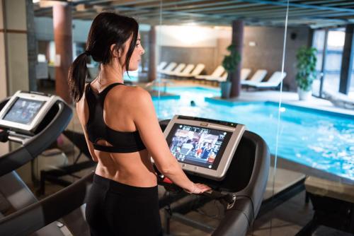 a woman running on a treadmill in front of a swimming pool at Hotel Veronesi La Torre in Dossobuono