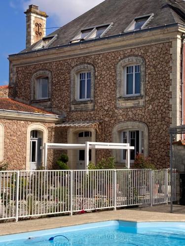 a house with a swimming pool in front of a building at La Villa des Roses Gîte Chambres d'hôtes Piscine chauffée in Luçon