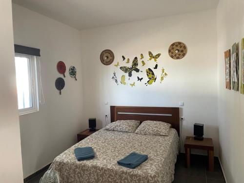 a bedroom with a bed and some butterflies on the wall at Villa sol e mar in Vila do Maio