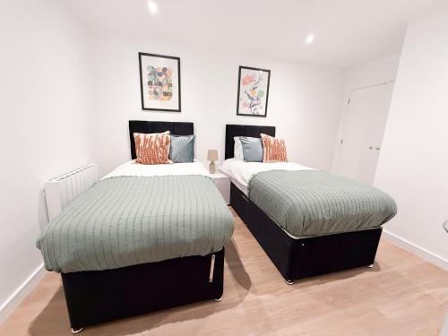 two beds in a room with white walls and wood floors at Spacious Modern 1 Bed Apartments in St Neots - Perfect for Contractors & Professionals - Free Parking - WiFi - Fully Equipped Kitchen - Smart TV Ideal for Work Stays and Long Projects in Saint Neots