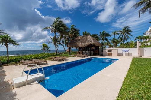 a swimming pool with a gazebo and the ocean at 2 BR Apartment sea view in Puerto Aventuras