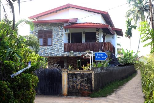 a house with a blue street sign in front of it at Muru's Place in Dickwella