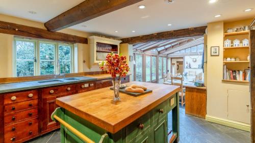 a kitchen with a wooden island with a vase of flowers at Coppice House in Ashton under Hill