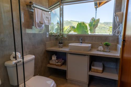a bathroom with a toilet and a sink and a window at Pousada São Gabriel in Barracão