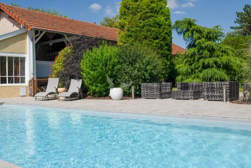 une piscine avec des chaises et une maison dans l'établissement L'Artbanne - Maison Hestia, à Saint-Hilaire-le-Petit