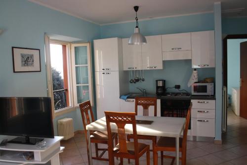 a kitchen with white cabinets and a table and chairs at Appartamento De Angeli in Laveno-Mombello