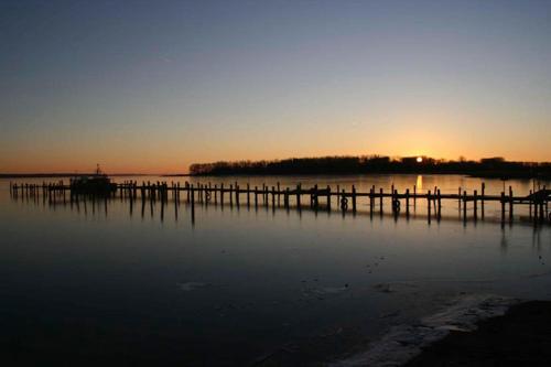 a dock on a body of water with the sunset at Herrenhaus Blengow App.06 in Blengow