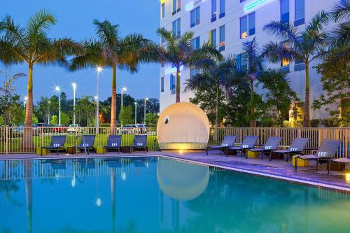 a swimming pool with chairs and a building at Aloft Miami Doral in Miami