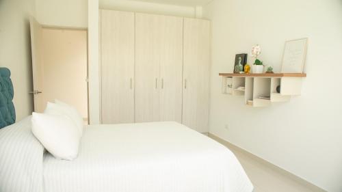 a white bedroom with a white bed and white cabinets at La Veranera in Girardot