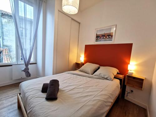 une chambre avec un grand lit et une grande fenêtre dans l'établissement L'Orangeade, à Cognac