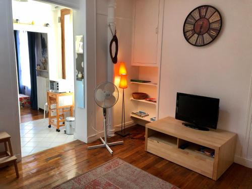Il comprend un salon doté d'une télévision à écran plat et d'un ventilateur. dans l'établissement Appartement calme Paris XXeme, à Paris