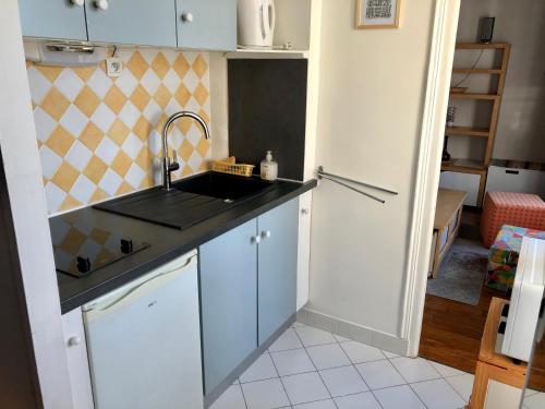 une cuisine avec un évier et un plan de travail dans l'établissement Appartement calme Paris XXeme, à Paris