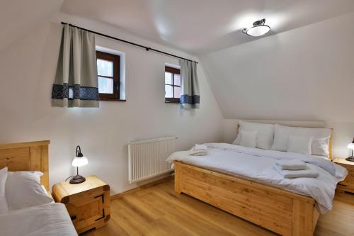 a bedroom with two beds and two windows at Zaži Chalupa Liptovska Osada in Liptovská Osada