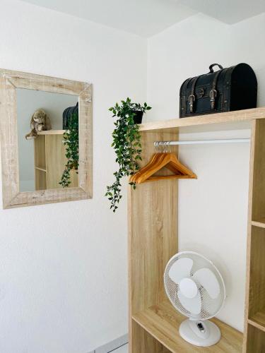 a wooden shelf with a mirror and a fan at Spacieux, lumineux et confortable in La Walck