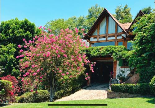 a house with a pink flowering tree in front of it at Chalet para 10 personas, alberca y jacuzzi in Valle de Bravo
