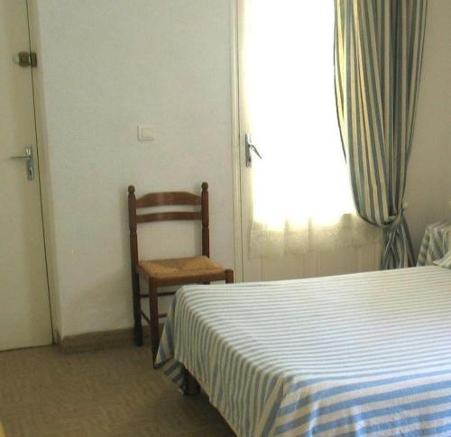 a bedroom with a bed and a chair and a window at Gite dans un cadre agreable in Salernes